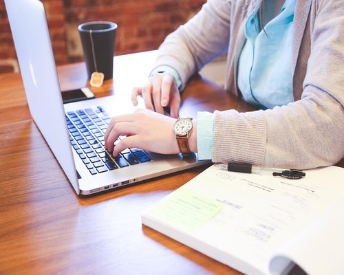 Person typing on a laptop with a comfortable posture in an office